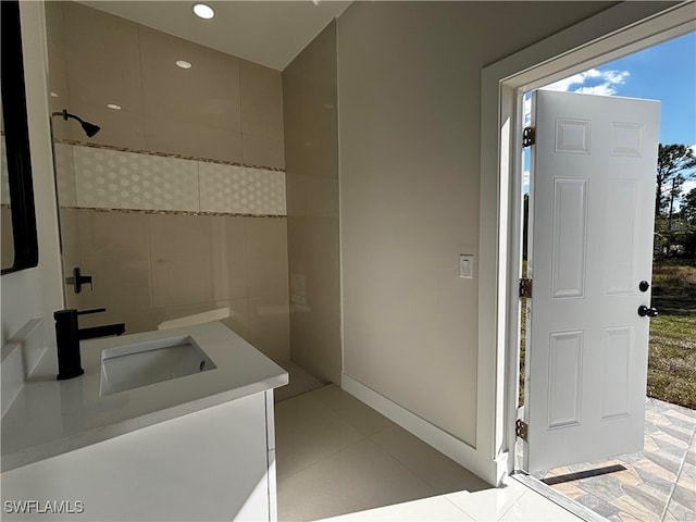 bathroom featuring a tile shower, vanity, and tile patterned floors