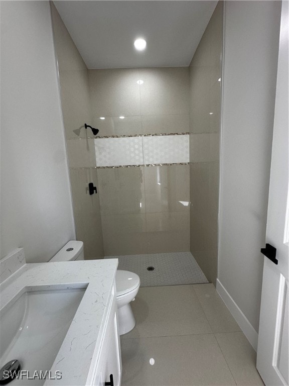 bathroom with tile patterned flooring, a tile shower, vanity, and toilet