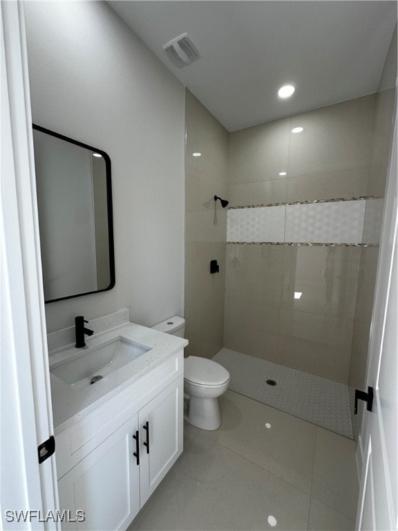 bathroom featuring tiled shower, tile patterned floors, vanity, and toilet