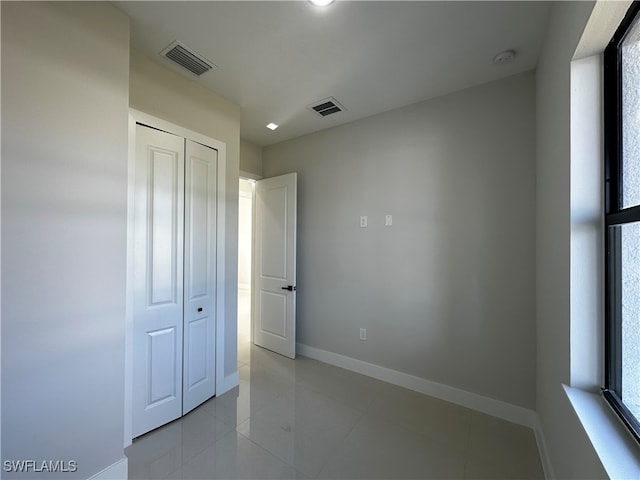 unfurnished bedroom with light tile patterned flooring and a closet