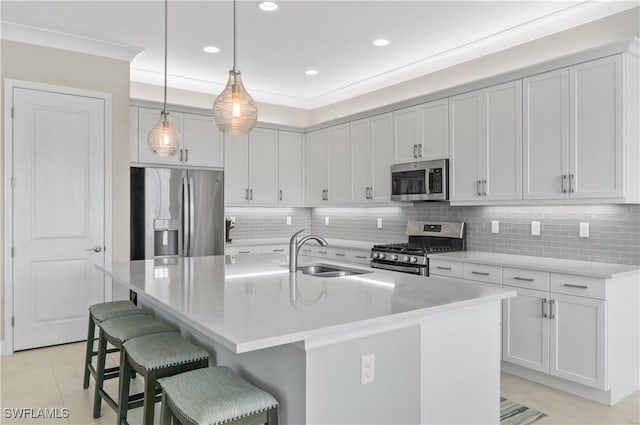 kitchen with sink, stainless steel appliances, a kitchen breakfast bar, decorative light fixtures, and a center island with sink