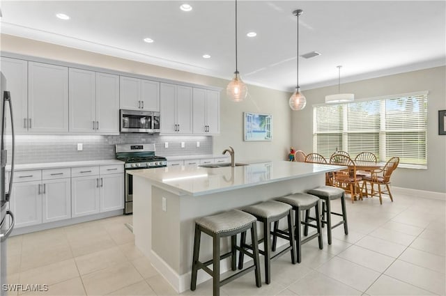 kitchen featuring a breakfast bar, a kitchen island with sink, sink, decorative light fixtures, and stainless steel appliances