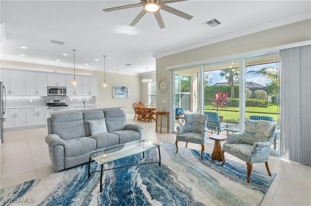 tiled living room featuring ceiling fan, crown molding, and sink