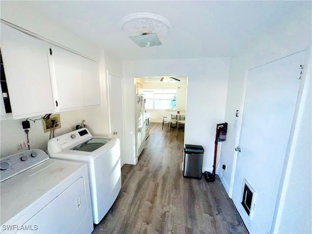 clothes washing area featuring dark hardwood / wood-style floors, cabinets, and washing machine and dryer