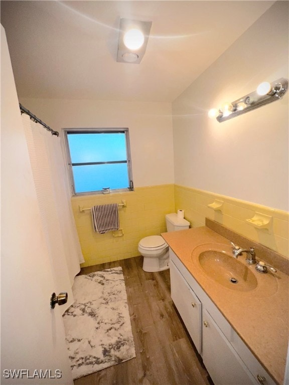 bathroom featuring wood-type flooring, vanity, toilet, and tile walls