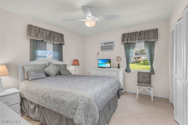 bedroom featuring ceiling fan, light tile patterned floors, an AC wall unit, and a closet