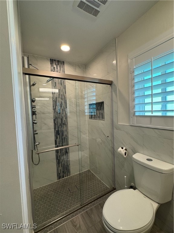 bathroom with toilet, walk in shower, and tile walls