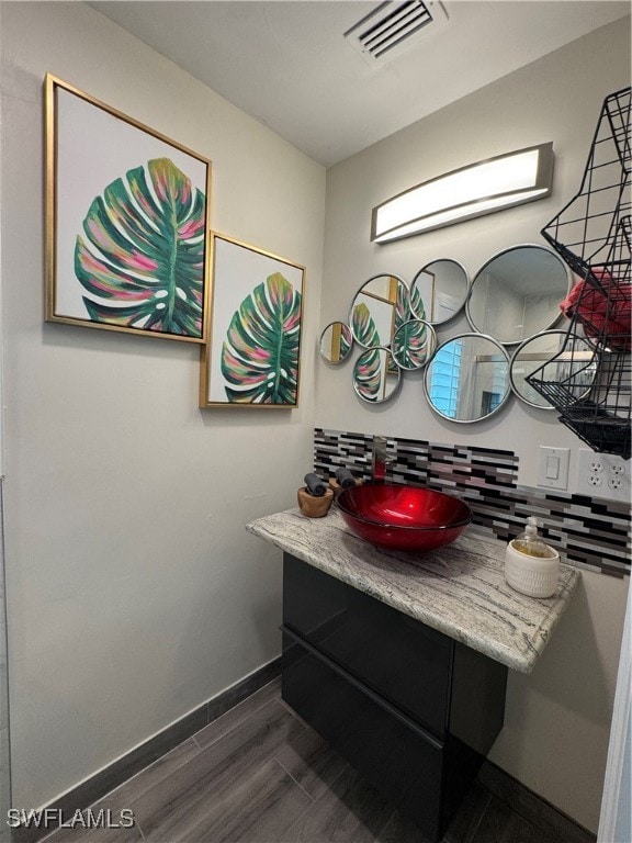 bathroom featuring wood-type flooring, vanity, and tasteful backsplash