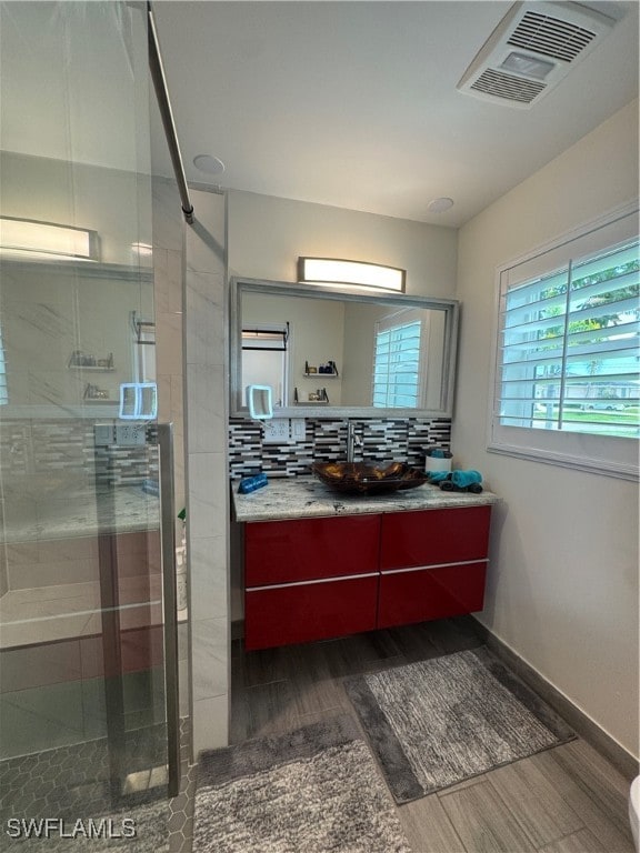 bathroom featuring decorative backsplash, hardwood / wood-style floors, vanity, and an enclosed shower