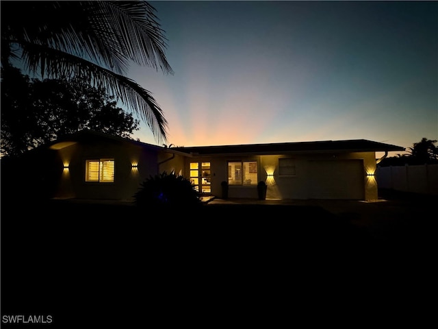 back house at dusk featuring a garage