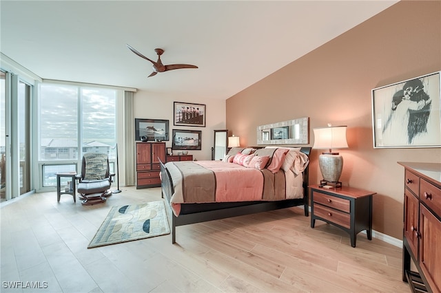 bedroom with expansive windows, light hardwood / wood-style flooring, and ceiling fan