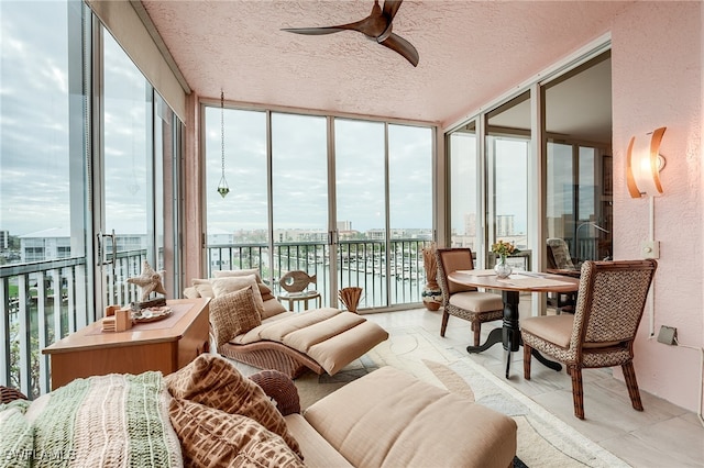 sunroom featuring a water view, ceiling fan, and a healthy amount of sunlight