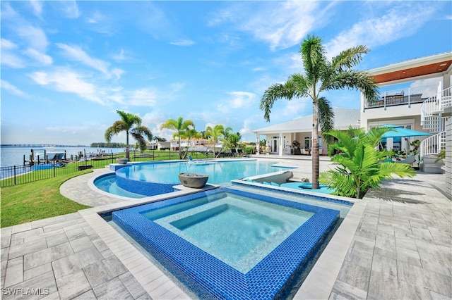 view of pool featuring a patio area, a water view, a yard, and an in ground hot tub