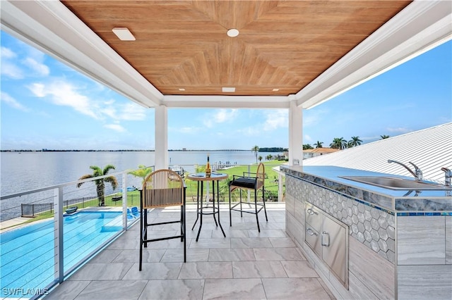 view of patio / terrace with an outdoor kitchen, a water view, and sink