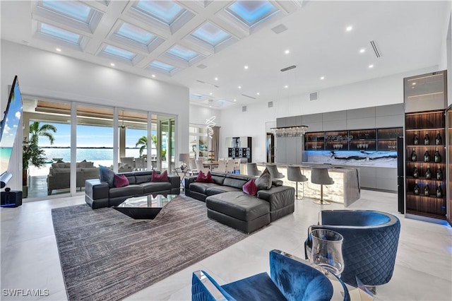 tiled living room with a water view, a towering ceiling, and coffered ceiling