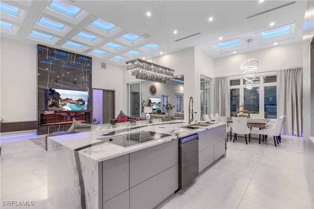 kitchen featuring gray cabinetry, a large island with sink, sink, hanging light fixtures, and black electric cooktop