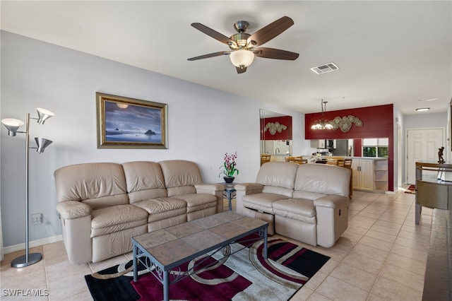 tiled living room with ceiling fan with notable chandelier