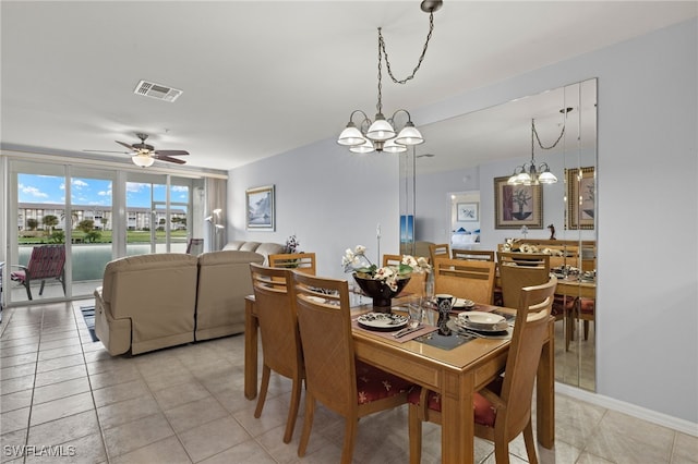 dining area with ceiling fan with notable chandelier, light tile patterned flooring, and a water view