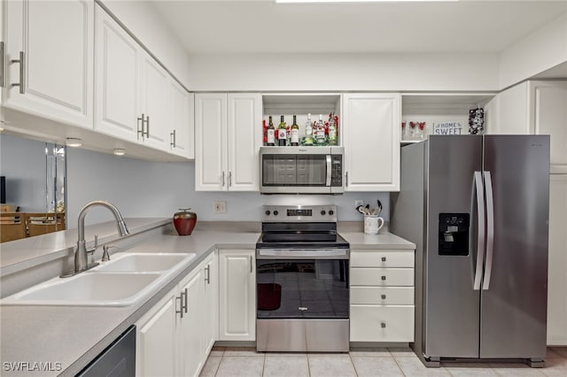 kitchen with light tile patterned flooring, appliances with stainless steel finishes, white cabinetry, and sink