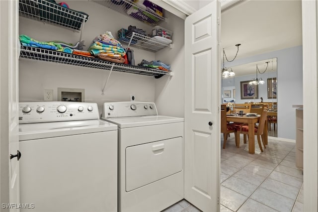 laundry area featuring light tile patterned floors, washer and dryer, and a notable chandelier