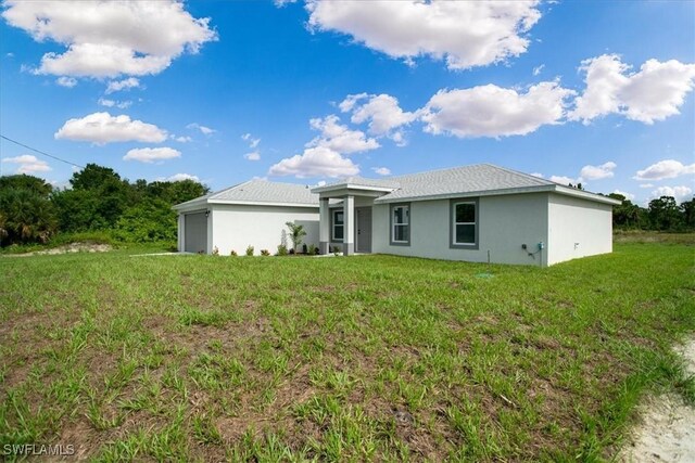 2902 40th St W, Lehigh Acres, FL 33971 - rear view of property featuring an attached garage, stucco siding, and a yard