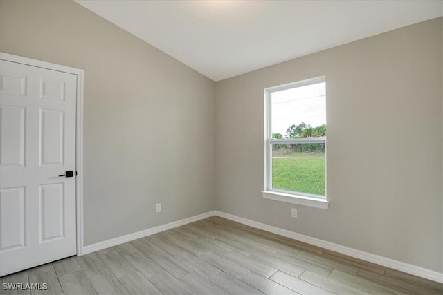 2902 40th St W, Lehigh Acres, FL 33971 - spare room featuring wood finish floors, baseboards, and vaulted ceiling