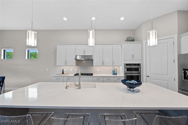 kitchen featuring a kitchen bar, a large island with sink, sink, and decorative light fixtures