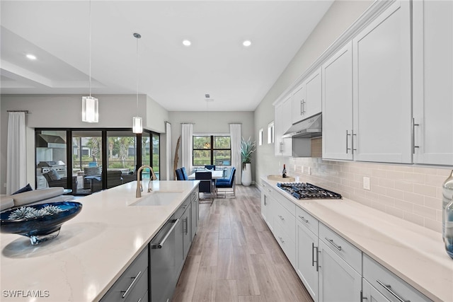 kitchen featuring light hardwood / wood-style flooring, white cabinetry, hanging light fixtures, and sink