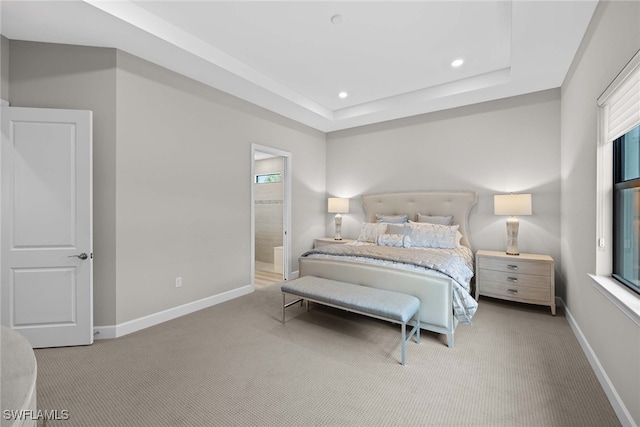 bedroom with ensuite bathroom and light colored carpet