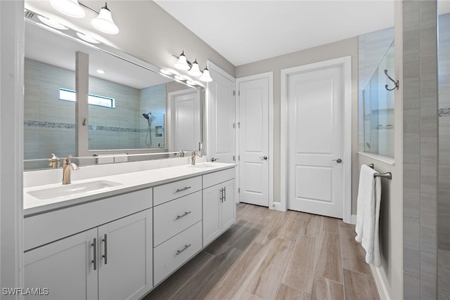 bathroom featuring vanity, a tile shower, and wood-type flooring