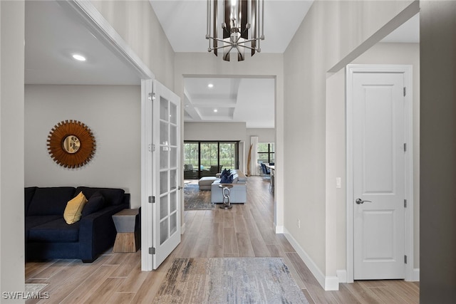 entryway featuring french doors, light wood-type flooring, and a notable chandelier