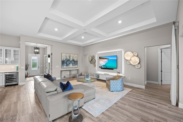 living room featuring coffered ceiling, wine cooler, light wood-type flooring, beamed ceiling, and a chandelier