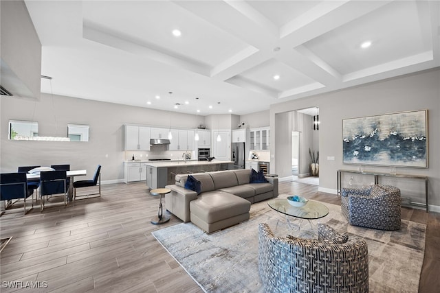 living room featuring coffered ceiling, beam ceiling, sink, and light hardwood / wood-style flooring