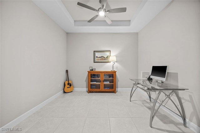 tiled home office featuring ceiling fan and a tray ceiling