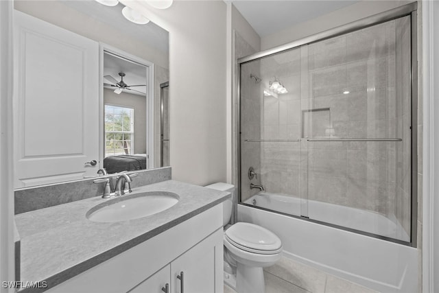 full bathroom with vanity, bath / shower combo with glass door, tile patterned flooring, ceiling fan, and toilet