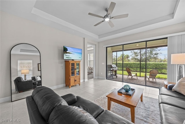 tiled living room featuring ceiling fan and a tray ceiling