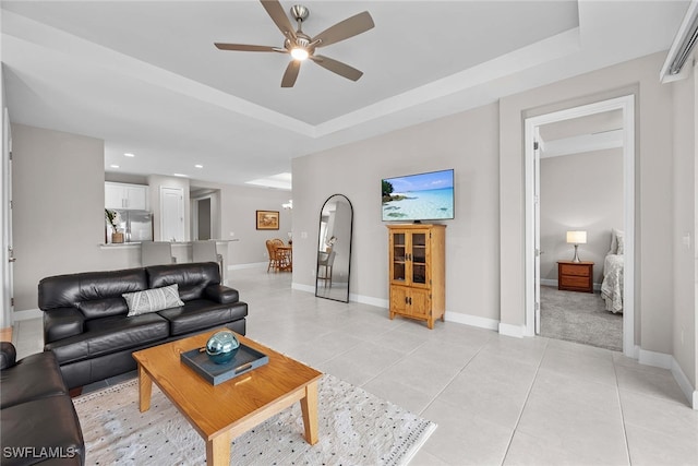 tiled living room featuring a tray ceiling and ceiling fan