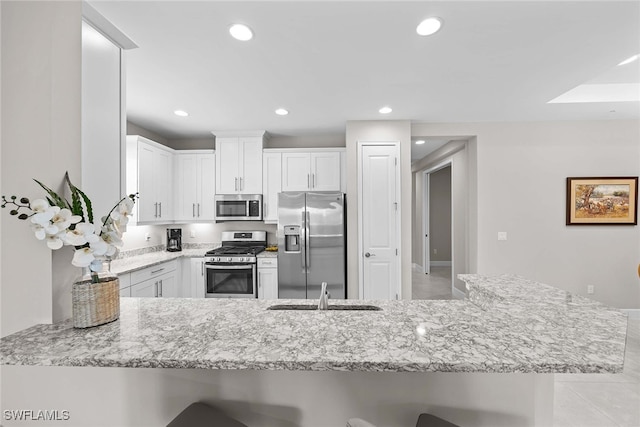 kitchen featuring white cabinetry, sink, a kitchen breakfast bar, kitchen peninsula, and appliances with stainless steel finishes