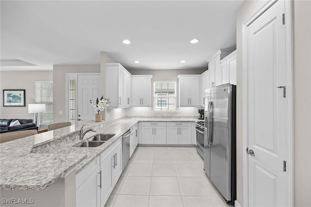 kitchen with light stone countertops, white cabinetry, sink, stainless steel appliances, and light tile patterned flooring