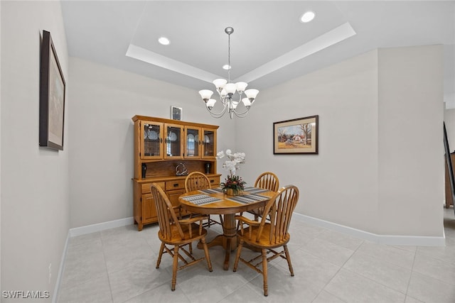 tiled dining area featuring an inviting chandelier and a tray ceiling