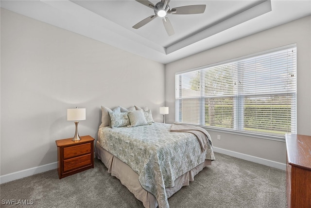 carpeted bedroom featuring ceiling fan and a tray ceiling