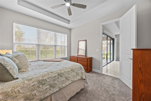 bedroom featuring access to outside, a raised ceiling, ceiling fan, and light colored carpet