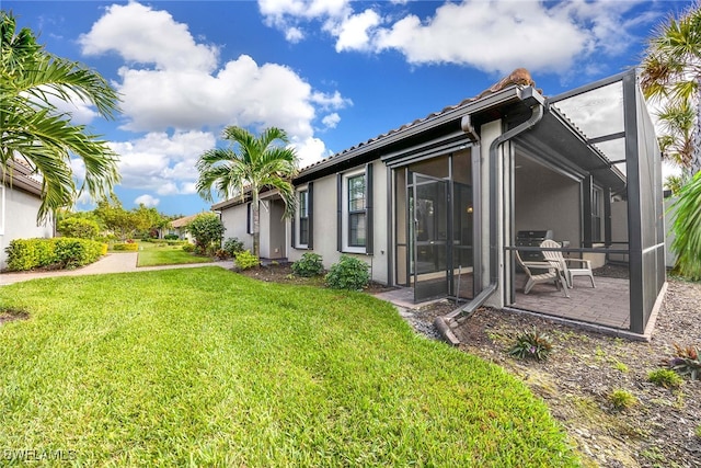 back of house featuring a lawn, a patio, and a lanai