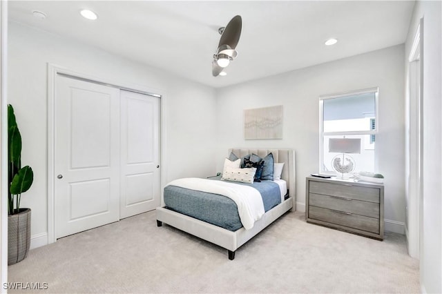 bedroom with ceiling fan, a closet, and light colored carpet