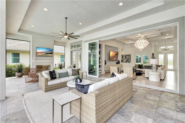 living room featuring french doors, ceiling fan with notable chandelier, and a tray ceiling