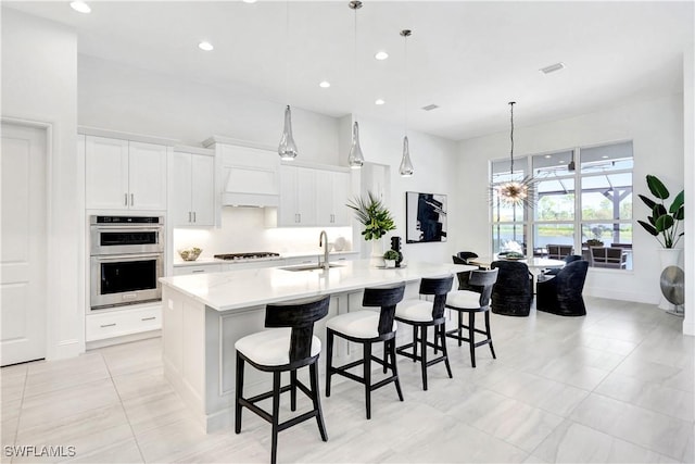 kitchen featuring pendant lighting, sink, stainless steel double oven, a large island, and white cabinetry