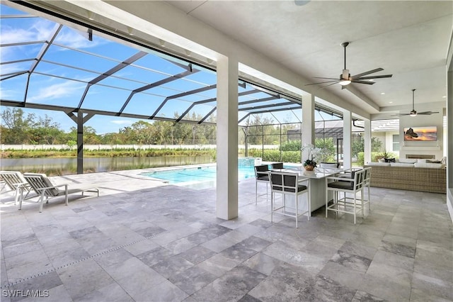 view of pool with a bar, an outdoor hangout area, a water view, and glass enclosure