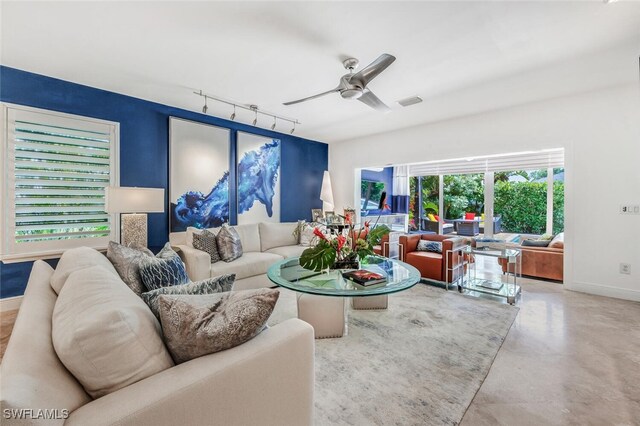 living room with rail lighting, ceiling fan, and concrete floors