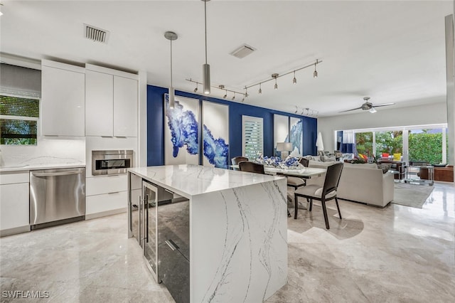 kitchen featuring a center island, white cabinetry, stainless steel dishwasher, and hanging light fixtures