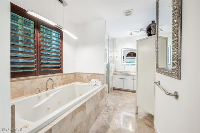 bathroom featuring vanity and a relaxing tiled tub